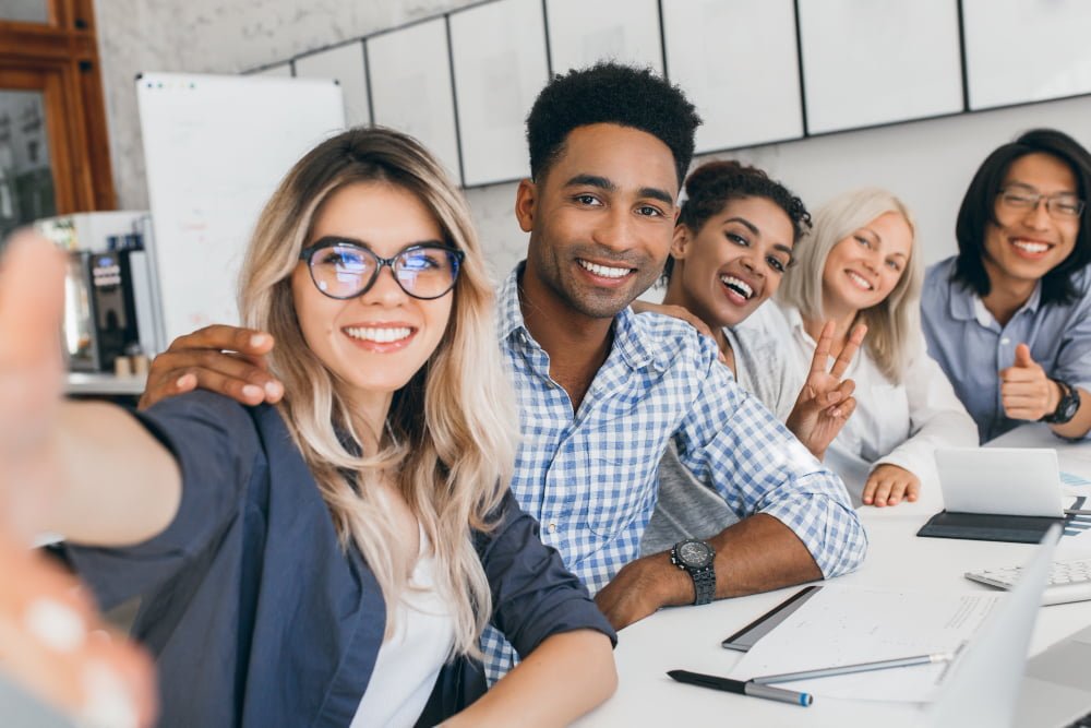 black-office-worker-in-checkered-shirt-embracing-blonde-secretary-woman-while-she-making-selfie-young-managers-of-international-company-having-fun-during-meeting.jpg